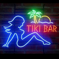 a neon sign that says tiki bar with a woman sitting on the beach next to it