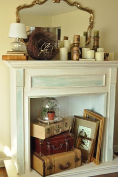 a white fireplace mantel topped with lots of suitcases and a clock on top