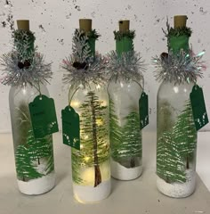 three bottles with trees in them are sitting on a table and have tags attached to them