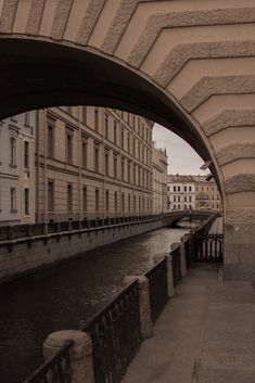 an arch in the side of a building over a river with buildings on both sides