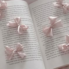 an open book with pink bows on it