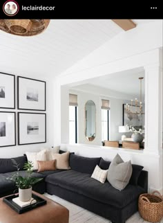 a living room with black couches and pictures on the wall above them, along with a coffee table