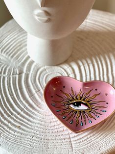 a pink heart shaped bowl sitting on top of a white mannequin head