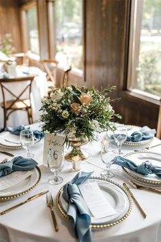 the table is set with plates, silverware and blue napkins for an elegant wedding reception