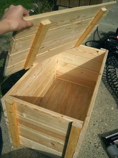 a person is holding a wooden box on the ground next to a motorcycle and other items