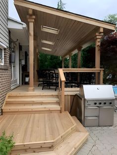 an outdoor kitchen and grill area with wooden steps leading up to the back porch,