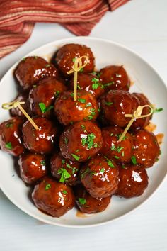 a white plate topped with meatballs covered in sauce and garnished with parsley