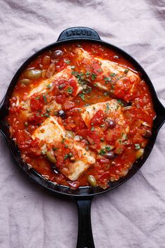 a pan filled with fish covered in tomato sauce