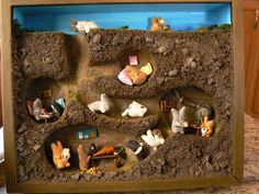 a wooden frame with many different animals in the sand and on top of it is a fake house