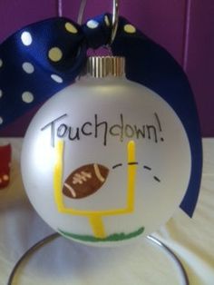 a glass ornament with a football on it and a polka dot bow around the neck