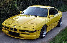 a yellow sports car parked on the side of a road next to grass and trees