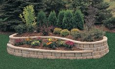 a flower bed in the middle of a lawn with trees and shrubs around it,