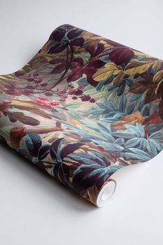 a rolled up wrapping paper on top of a white surface with an image of flowers and leaves