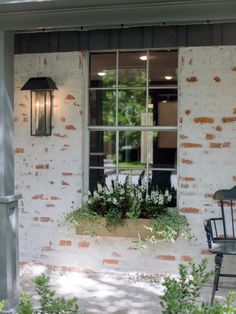 a chair sitting in front of a window next to a planter filled with flowers