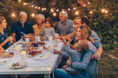 a group of people sitting around a table with plates of food and drinks on it