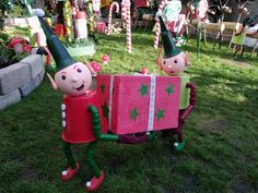 two garden gnomes with gifts in their hands on the grass near christmas decorations and candy canes