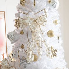 a white christmas tree decorated with gold and silver ornaments