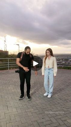 a man and woman standing on top of a brick walkway next to each other with the sky in the background