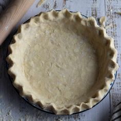 an uncooked pie crust in a blue dish with a wooden spoon next to it