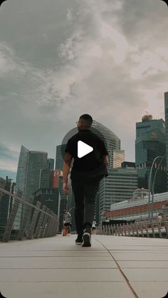 a man walking across a bridge with the city in the backgrounds