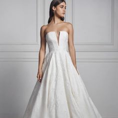 a woman in a white wedding dress standing against a wall