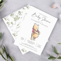 a baby shower with winnie the pooh on it and greenery next to it