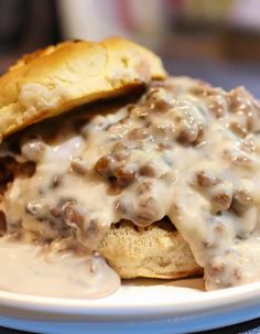 a hamburger covered in gravy sitting on top of a white plate