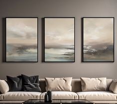 three paintings hang on the wall above a couch in a living room with a coffee table