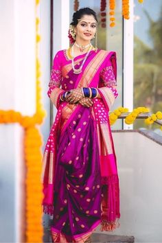 a woman in a purple and pink sari standing on steps with flowers around her