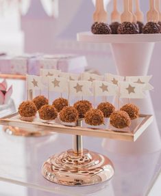 desserts are displayed on small gold trays with white stars and star - shaped decorations