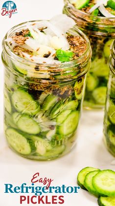 three mason jars filled with cucumber pickles on top of a white table