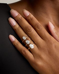 a woman's hand with three diamond rings on her left and the other hand holding an engagement ring