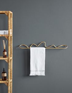 a bamboo shelf with towels hanging on it next to a towel rack and soap dispenser