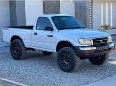 a white pick up truck parked in front of a building with black tires and rims