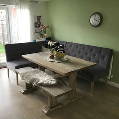 a table and bench in a room with a clock on the wall