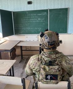 a soldier sitting in front of a chalkboard with writing on it's back