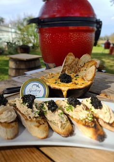 an assortment of appetizers are displayed on a white plate with a red pot in the background