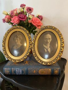 two frames sitting on top of a table next to flowers