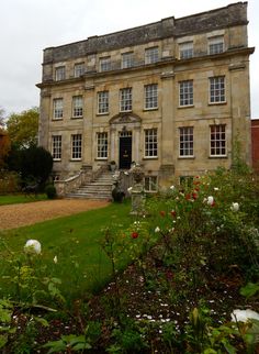 an old stone building with lots of windows and flowers in front of the entrance to it