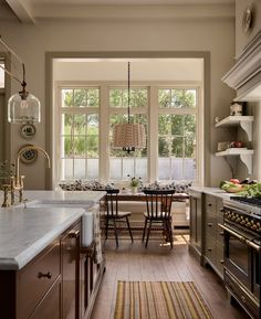 a kitchen with an island, sink and stove top oven next to two large windows