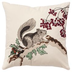 a pillow with an image of a squirrel sitting on a tree branch and berries in the background