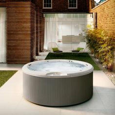 a large hot tub sitting on top of a lush green field next to a brick building