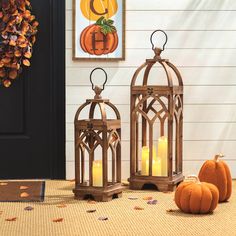 two wooden lanterns sitting on top of a rug next to pumpkins and a door