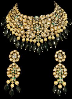 Nirvaan - Indian Bridal Jewelry Choker & Earrings of Kundan & Emerald for Brides Contemporary Indian bridal set with precious pearls and Kundan. This bridal choker jewelry set is accented with precious green gemstones making it one of a kind. Gold plated choker with emerald drops adorns this bridal necklace.  With its elaborating circular handcrafted design, this modern choker will make you feel like a million bucks. This short choker necklace comes with a beautiful pair of dangling earrings wit Indian Bridal Jewelry, Gold Temple Jewellery, Bridal Choker, Choker Jewelry, Choker Style Necklace, Bollywood Jewelry, Bridal Jewellery Indian, Emerald Pendant, Jewelry Choker