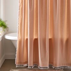 an orange shower curtain in a bathroom next to a bathtub with a potted plant on the window sill