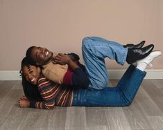 a man and woman laying on the floor with their arms around each other, smiling