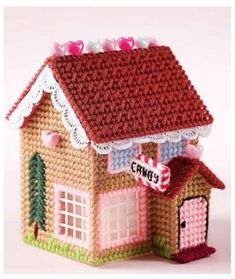 a crocheted dollhouse with a red roof and pink trimmings on it