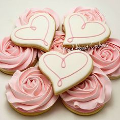 decorated cookies in the shape of hearts with pink frosting on top and roses around them