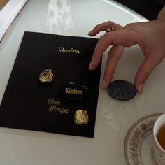 a person's hand is touching some kind of brooch on top of a table