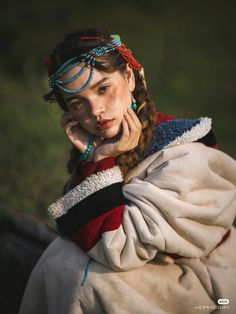 a young woman dressed in native american clothing poses for a photo with her hands on her face